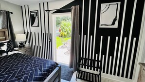A bedroom with a bed, a nightstand, a lamp, a window, and a door leading to a balcony. - #7 Heated Pool, Private Patio & Grill (Fort Lauderdale)
