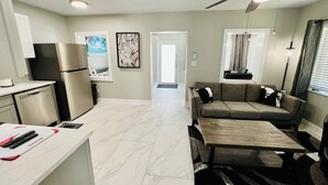 A modern kitchen with a built-in oven, a dining area with a wooden table, and a living room with a sofa and a ceiling fan. - #7 Heated Pool, Private Patio & Grill (Fort Lauderdale)