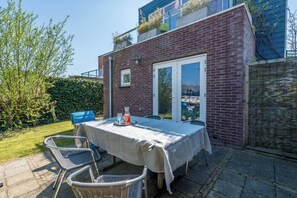 A patio with a table set for two, a blue chair, and a wicker chair.