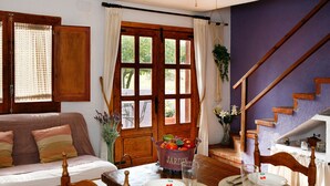 Un comedor con una mesa de madera dispuesta para dos personas, una silla de madera, un frutero y vistas a una escalera.