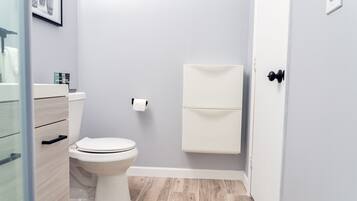 Un baño con inodoro, armario y zona de ducha.