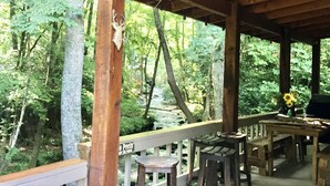 A wooden deck with a railing, a table, and several stools.