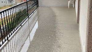 A balcony with a concrete floor, a metal railing, and a view of houses in the background. - Upper floor housing (Verín)