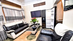 Un salon avec un canapé noir et blanc, une table basse et un téléviseur à écran plat.