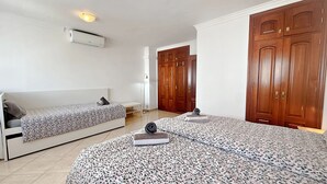 Une chambre avec deux lits, une armoire et un ventilateur de plafond.
