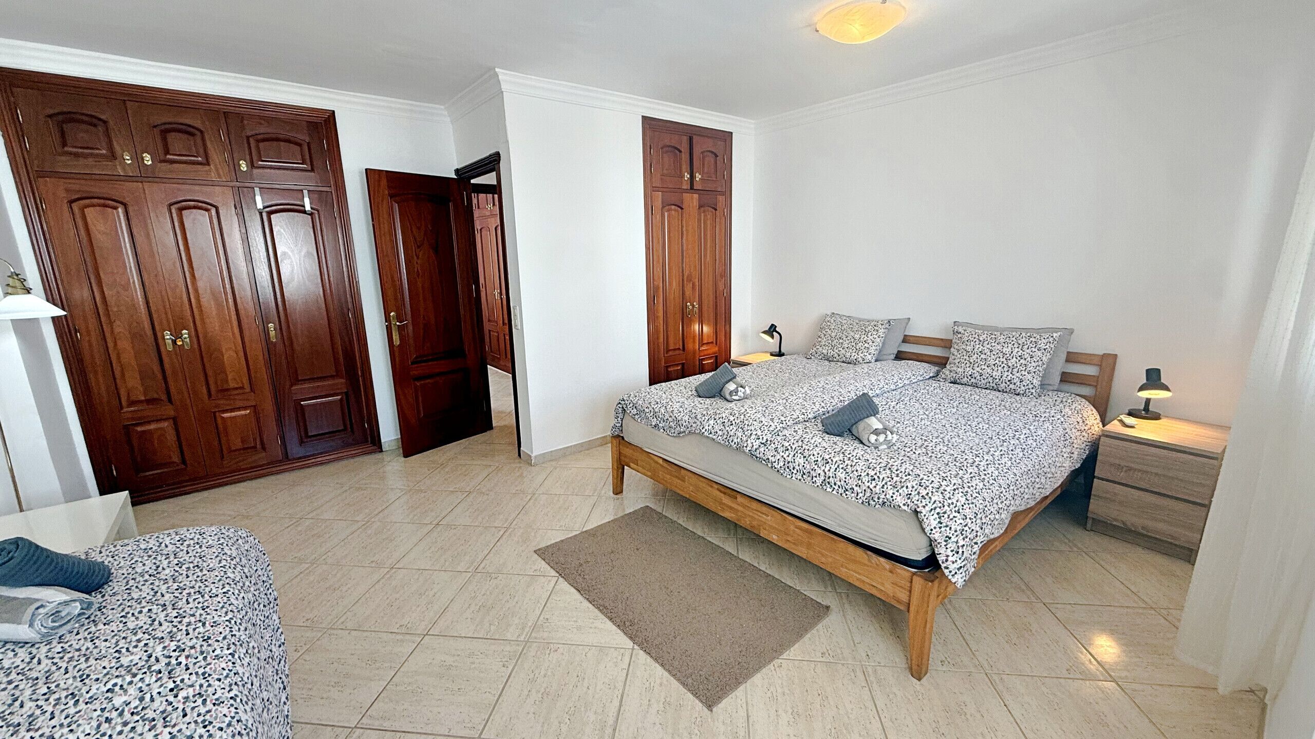 Ein Schlafzimmer mit Bett, Nachttischen, einem Schrank und einer Tür.