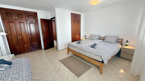 A bedroom with a bed, bedside tables, a nightstand, a wooden wardrobe, and a door.