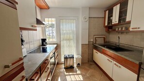 A compact kitchen with a stove, sink, and cabinets.