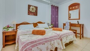 Quarto com cama de casal, duas mesas de cabeceira, mesa de apoio, escrivaninha, cadeira, espelho e ventoinha de teto.