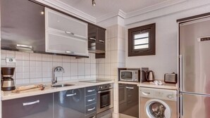 Uma cozinha moderna com eletrodomésticos de aço inoxidável, forno embutido, micro-ondas e máquina de lavar.