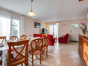 A dining area with a table set for breakfast, wooden chairs, and a red sofa in the background.