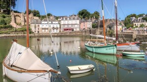 A harbor with several boats docked, a stone wall, and buildings in the background. - L'Olivier by Interhome (Erdeven)