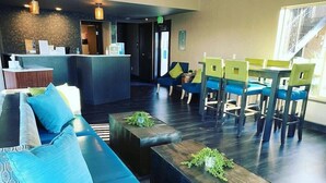 A modern lobby with a reception desk, seating area, and a staircase. - The Hotel Y, a Dazzler Select by Wyndham (YAKIMA)