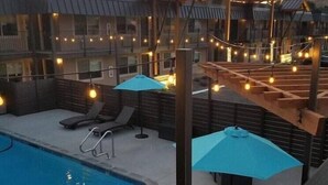 A pool area with lounge chairs, umbrellas, and a wooden deck. - The Hotel Y, a Dazzler Select by Wyndham (YAKIMA)