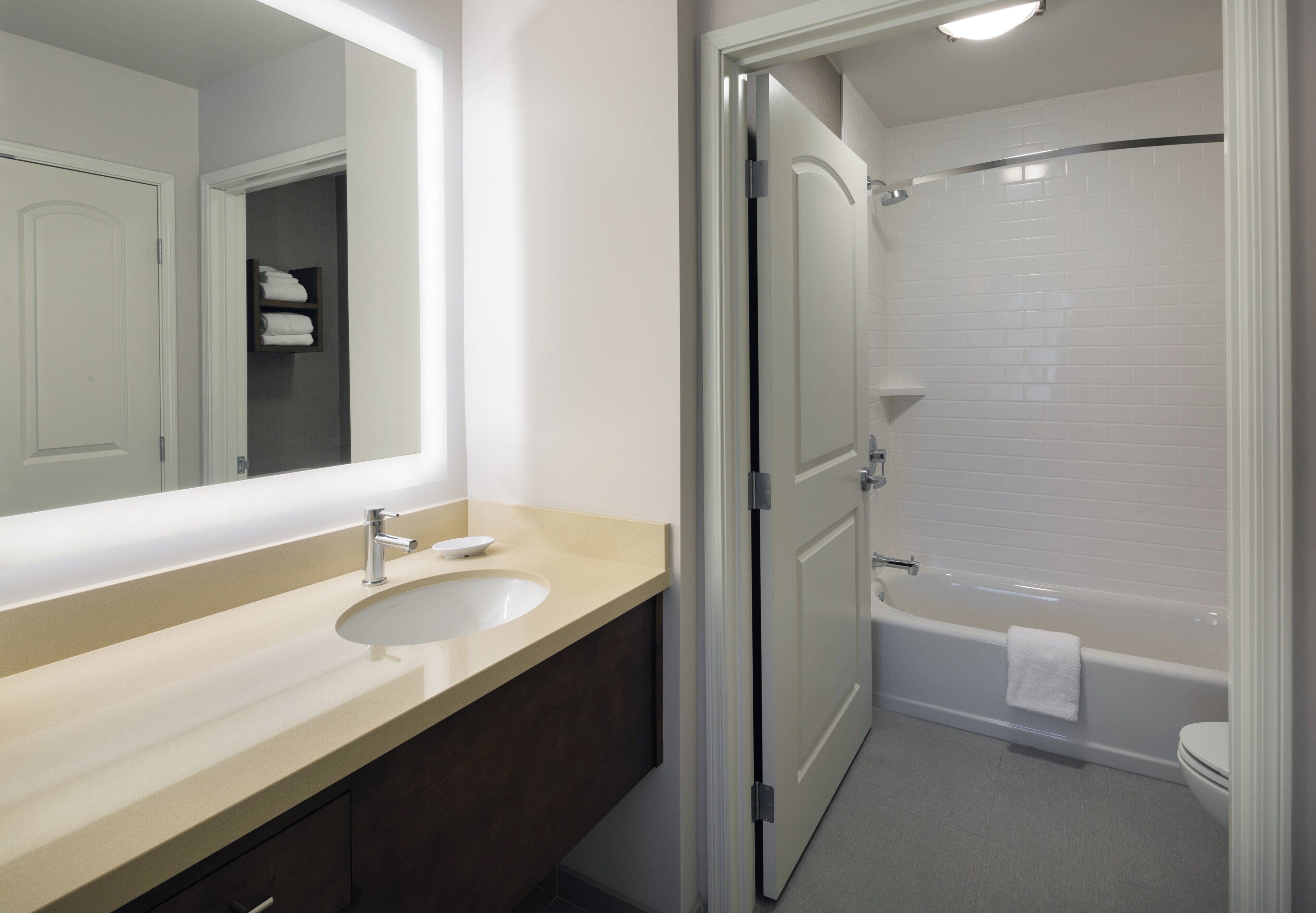 A bathroom with a sink, mirror, towel rack, and a bathtub.