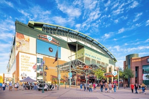 Un estadio con un gran letrero de Chase Field, una entrada cubierta y una multitud de personas.