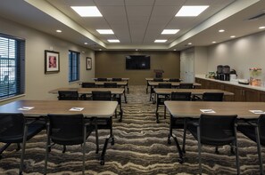A conference room with a large screen, multiple tables, and chairs. - Staybridge Suites Phoenix - Biltmore Area by IHG (Phoenix)