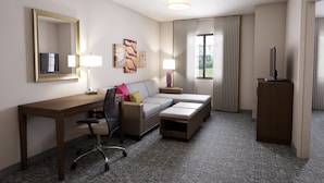 Une chambre d’hôtel équipée d’un bureau, d’un canapé, d’une télévision et d’une armoire.