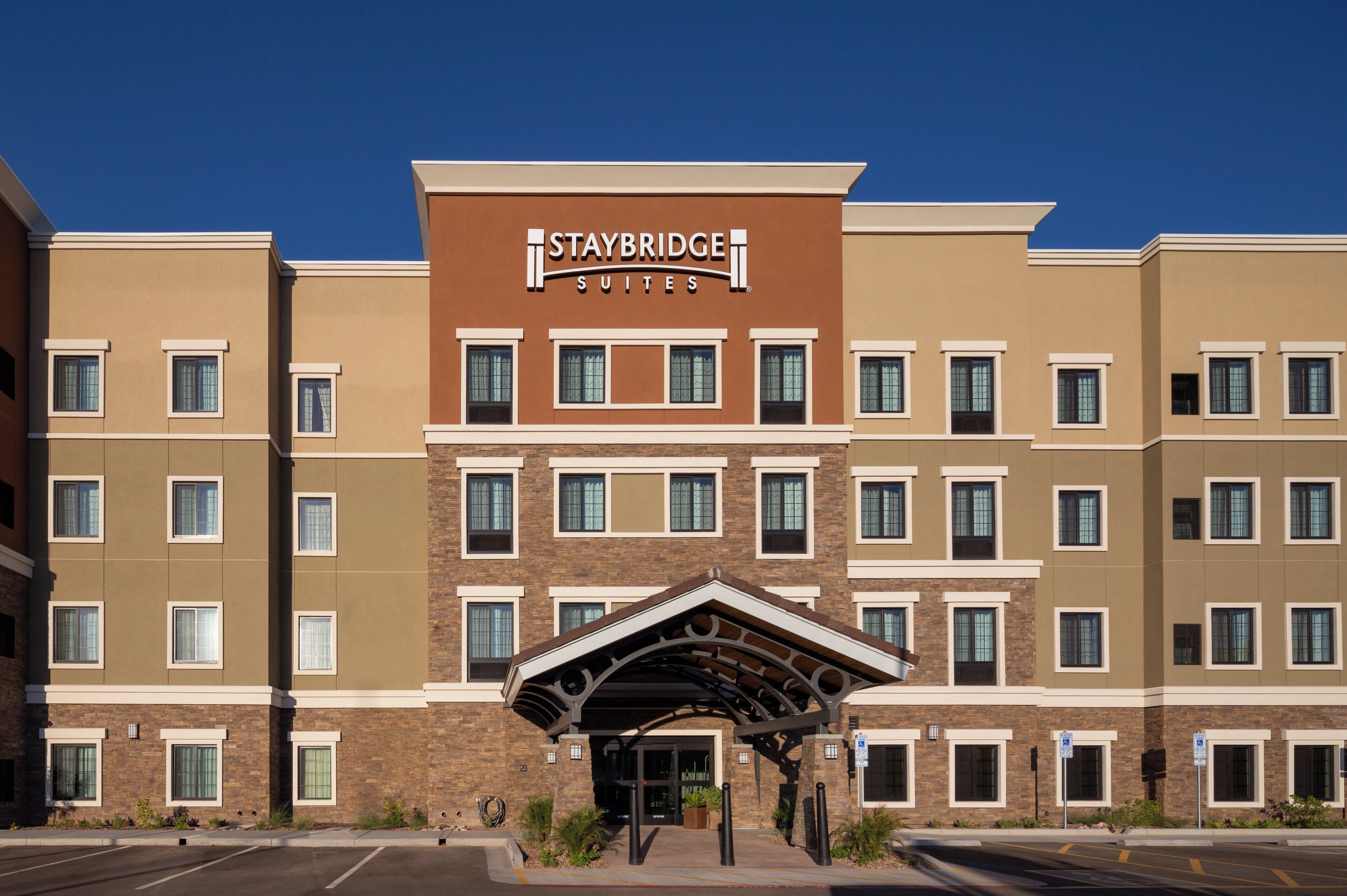 A Staybridge Suites hotel building with a modern architectural design, featuring multiple windows and a covered entrance.