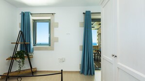 A room with a bed, a window with curtains, a plant on a stand, and a view of the outdoors. - Endless Blue View, Top Beaches Nearby (Rethymno)