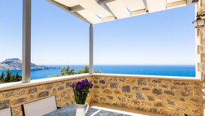 A stone-walled balcony with a table and chairs, overlooking a clear blue sea and distant mountains. - Endless Blue View, Top Beaches Nearby (Rethymno)