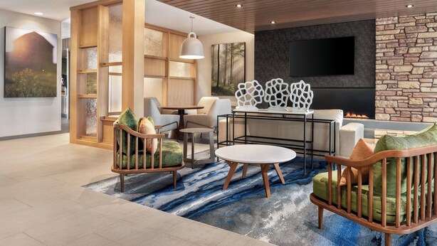 A modern living room with a fireplace, comfortable seating, and a large TV. - Fairfield Inn & Suites by Marriott Milwaukee West (Milwaukee)