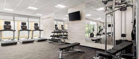 A gym with treadmills, weight machines, and a bench.
