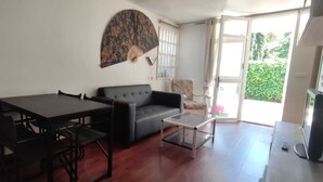 Een woonkamer met een eettafel, bank en een decoratieve ventilator.