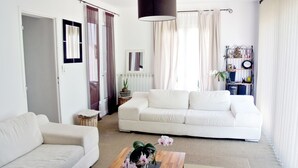 A living room with a white sofa, a wooden coffee table, and a hanging light fixture.