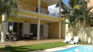 Un bâtiment à deux étages doté d’un balcon, d’une piscine et d’un espace extérieur aménagé pour s’asseoir.
