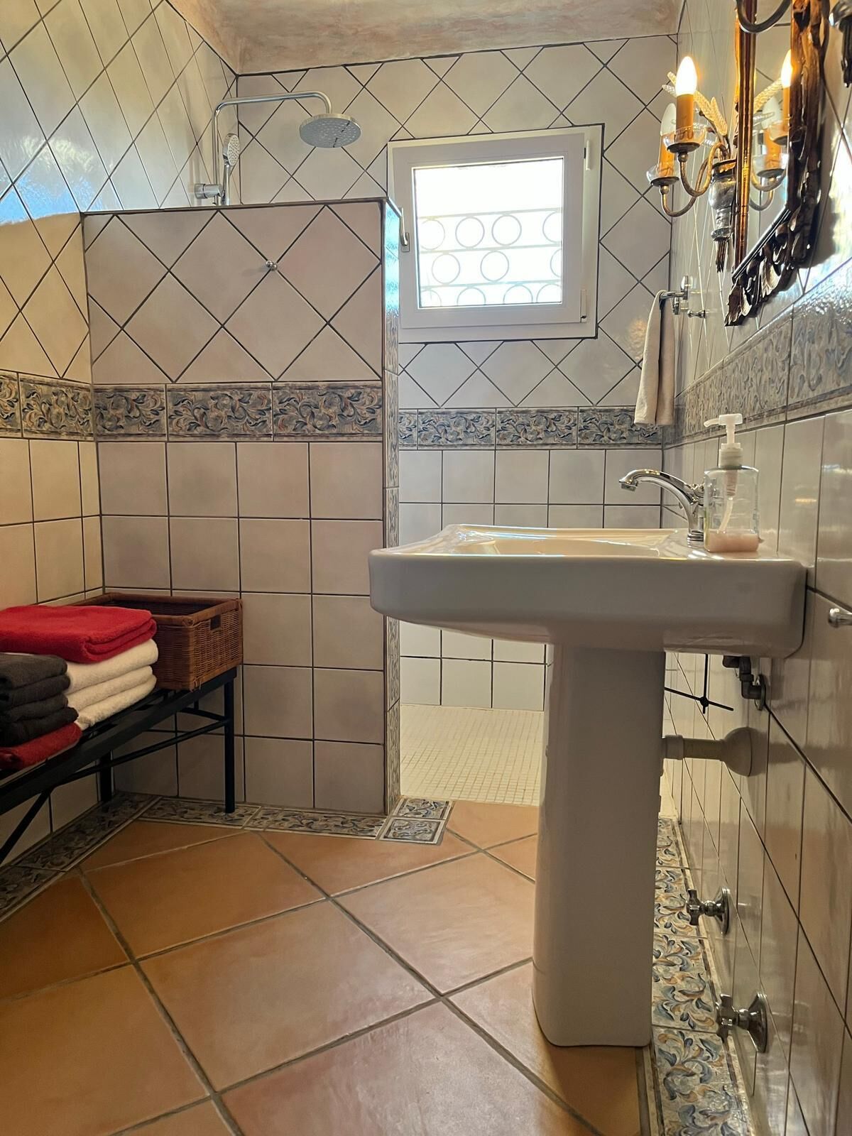 A bathroom with a shower, a sink, and a window.