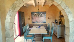 A dining area with a stone archway, a wooden table, and blue chairs.
