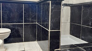 Un baño con baldosas de mármol blanco y negro, un inodoro blanco y una zona de ducha.