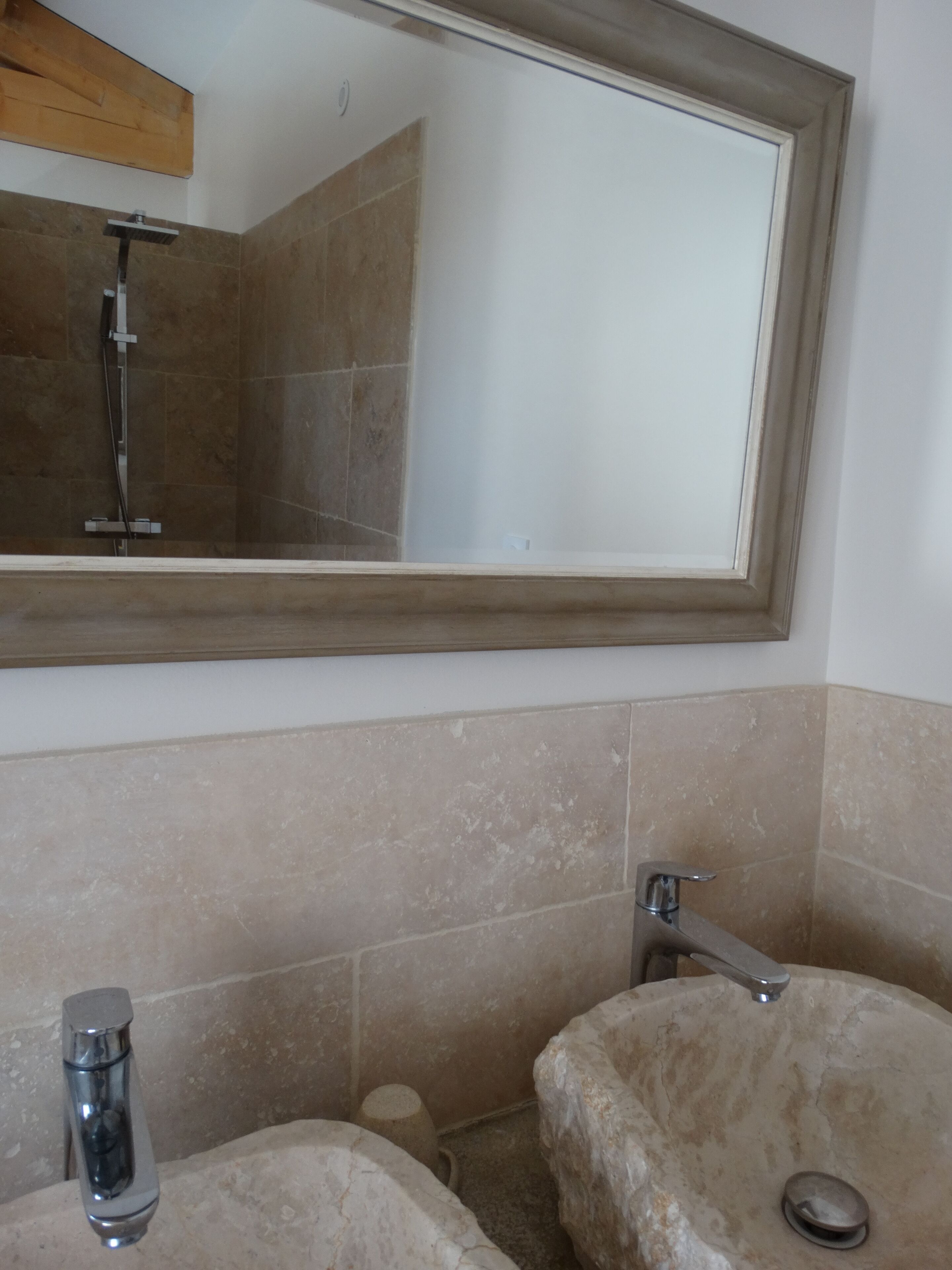 A bathroom with a large mirror, two sinks, and a shower.