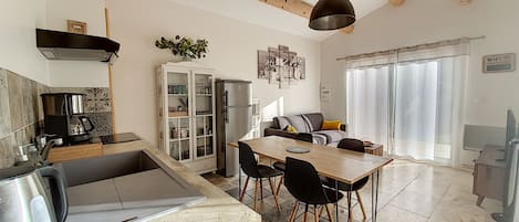 A modern kitchen with a dining area, wooden beams, a refrigerator, and a coffee maker.