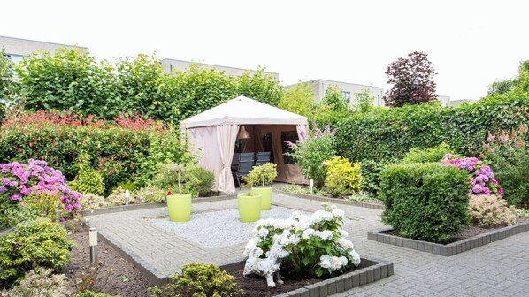 Relax in a serene garden setting with a tranquil outdoor space featuring a dining area and lush greenery.