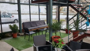 A covered outdoor seating area with a sofa, chairs, and potted plants. - Résidence Les Mélèzes de Prades (Prades)