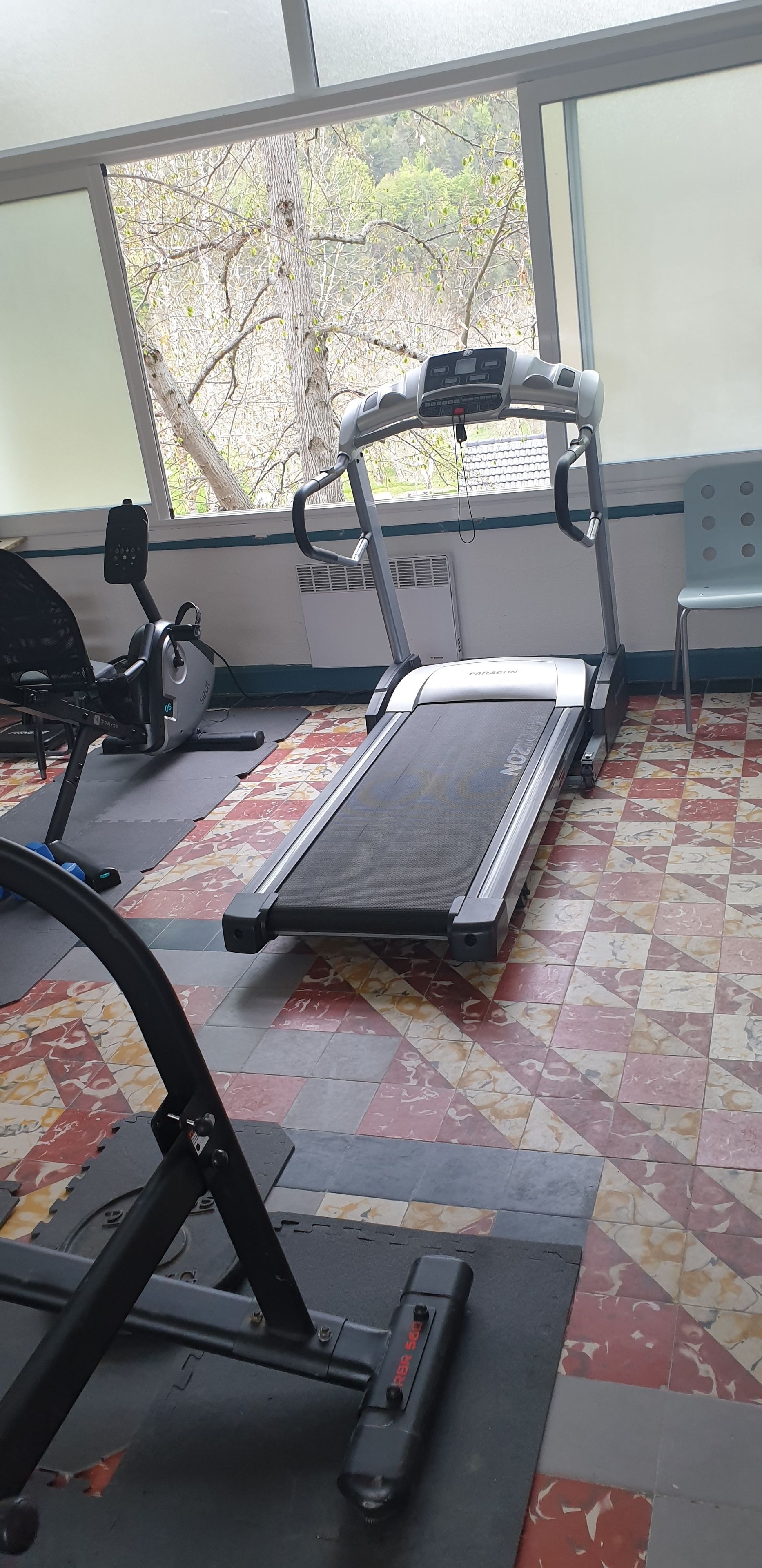 A gym with exercise equipment including a treadmill and an elliptical machine.