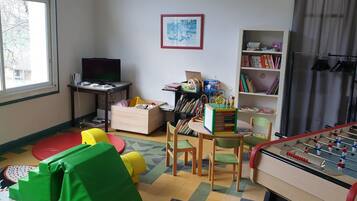 Una camera adatta ai bambini con tavolo da calcio, libreria, scrivania con computer e posti a sedere colorati.