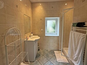 Une salle de bain avec une douche, un lavabo, une fenêtre et un porte-serviettes.