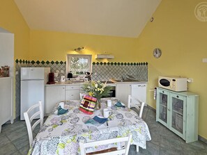 Una cocina compacta con comedor, refrigerador, microondas y pileta.