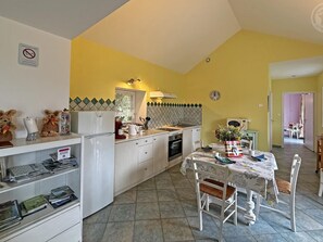Une cuisine compacte comprenant un coin repas, un réfrigérateur, une cuisinière et une table à manger avec des chaises.
