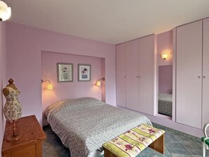 Une chambre à coucher comprenant un lit, une armoire, un banc et un mannequin.