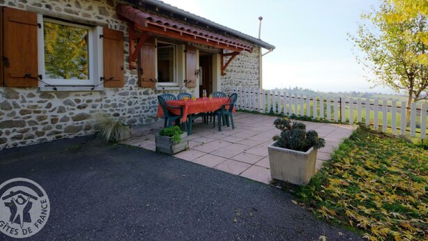 Un edificio de piedra con un patio, una mesa y sillas, y vistas al campo.