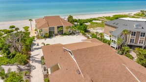 A beachfront property with multiple buildings, a sandy beach, and a clear view of the ocean.