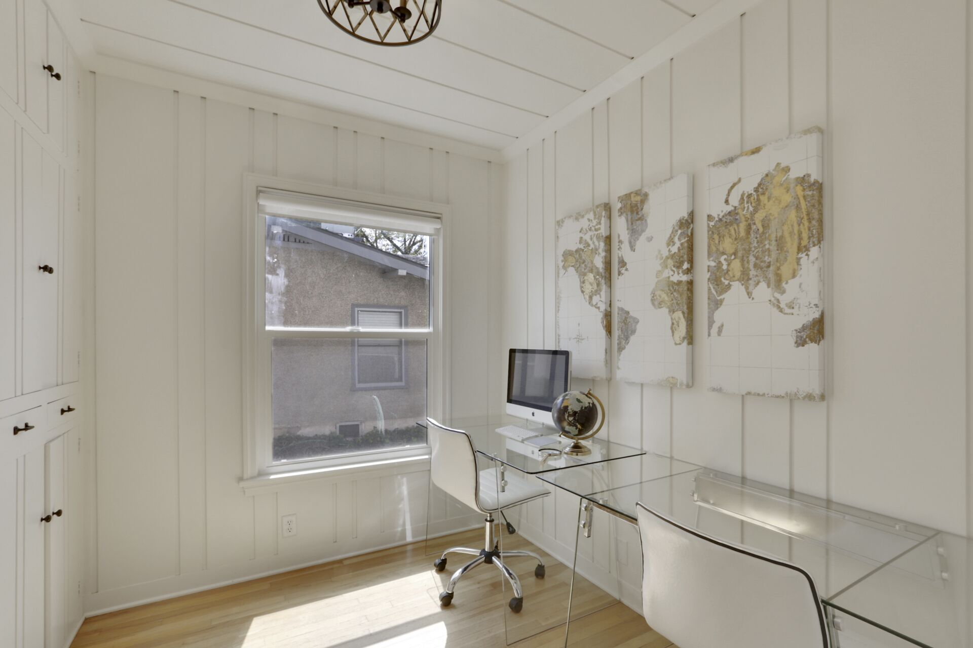 A modern office space with a glass desk, a computer, and a globe.