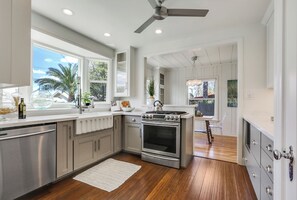 A modern kitchen with stainless steel appliances, white cabinetry, and a wooden floor. - Designer-luxury Park House in Charming Exeter (Exeter)