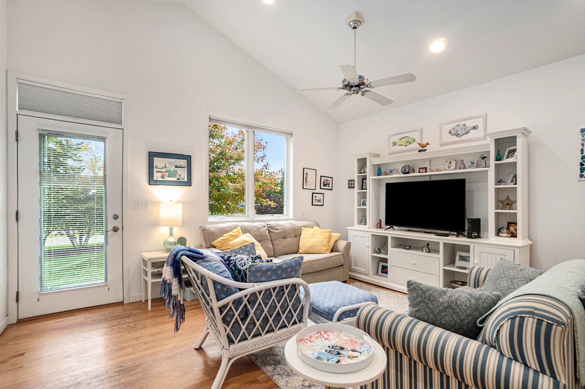 A living room with a sofa, armchair, TV, and shelves.