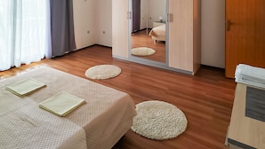 Un dormitorio con cama, armario, espejo y escritorio.