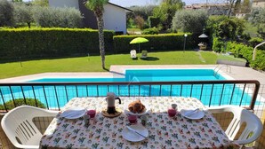 A patio with a pool table, chairs, and a table set for two with a cactus-patterned tablecloth. - La Palma - Apartment with terrace and pool view (Lazise)